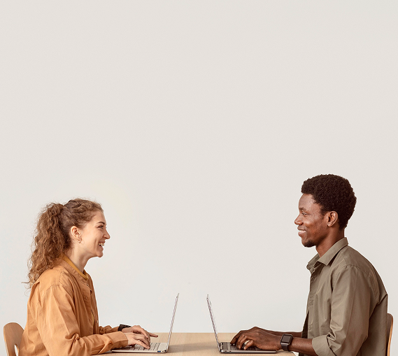 Two professionals smiling while working on laptops