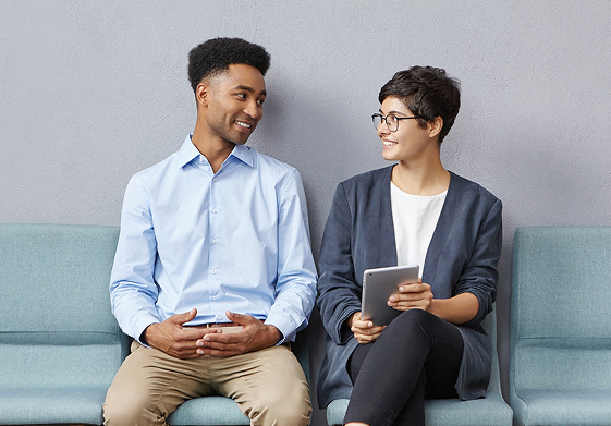 Two hiring professionals talking while seated on a sofa